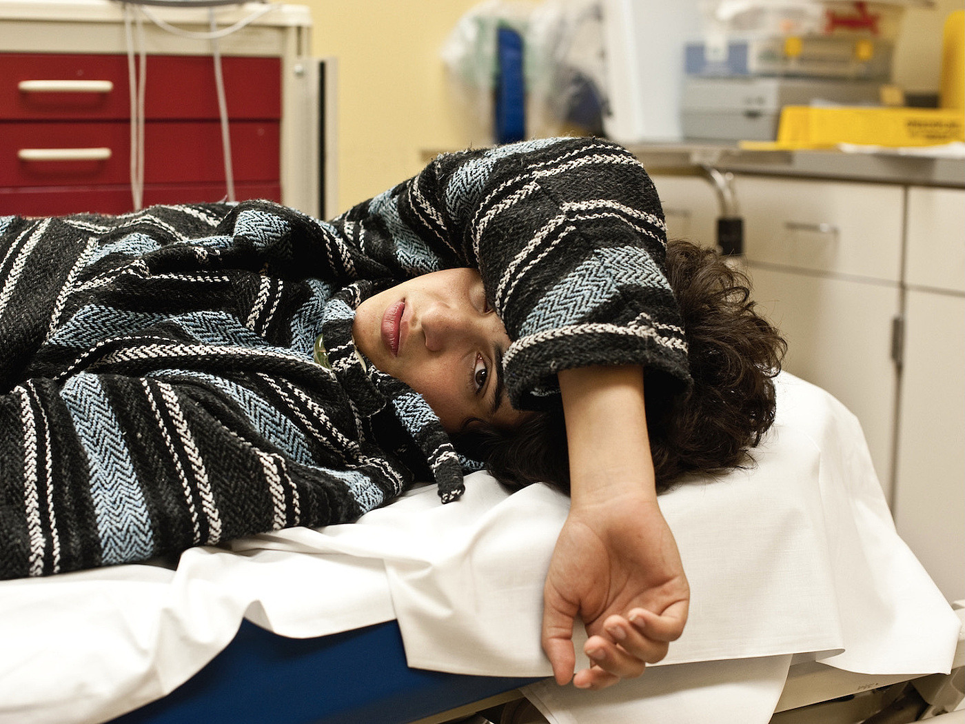 Junge Frau liegt angezogen in einem Krankenhausbett
